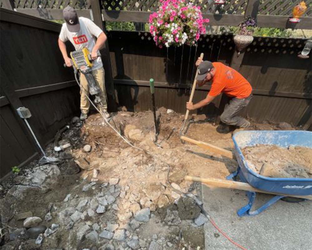 workers working on landscaping patio area bend or